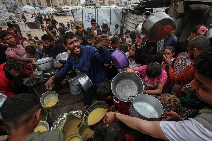 Nội các Israel cho phép nối lại viện trợ nhân đạo vào Gaza Người dân Palestine nhận thức ăn cứu trợ tại thành phố Gaza ngày 12-5-2025. (Ảnh: THX/TTXVN)